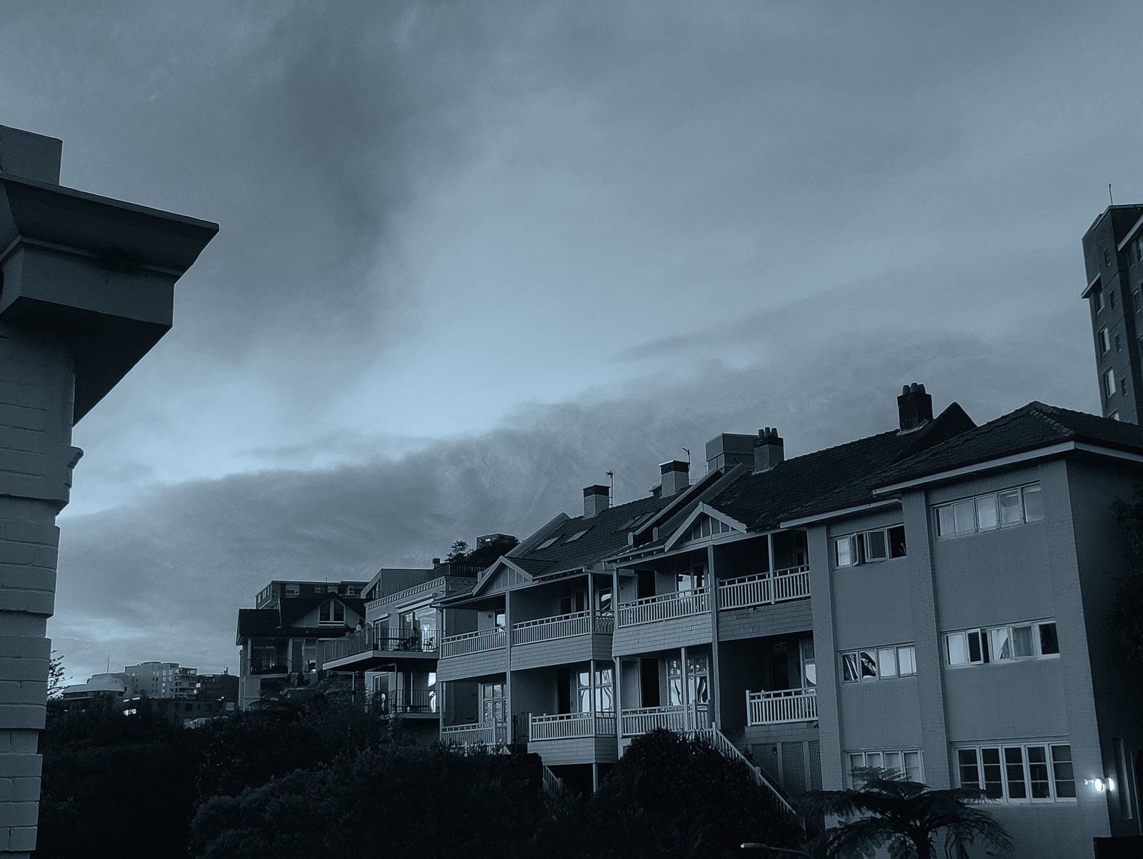 A duotone photograph of Kirribilli rooftops under a Sydney evening sky.